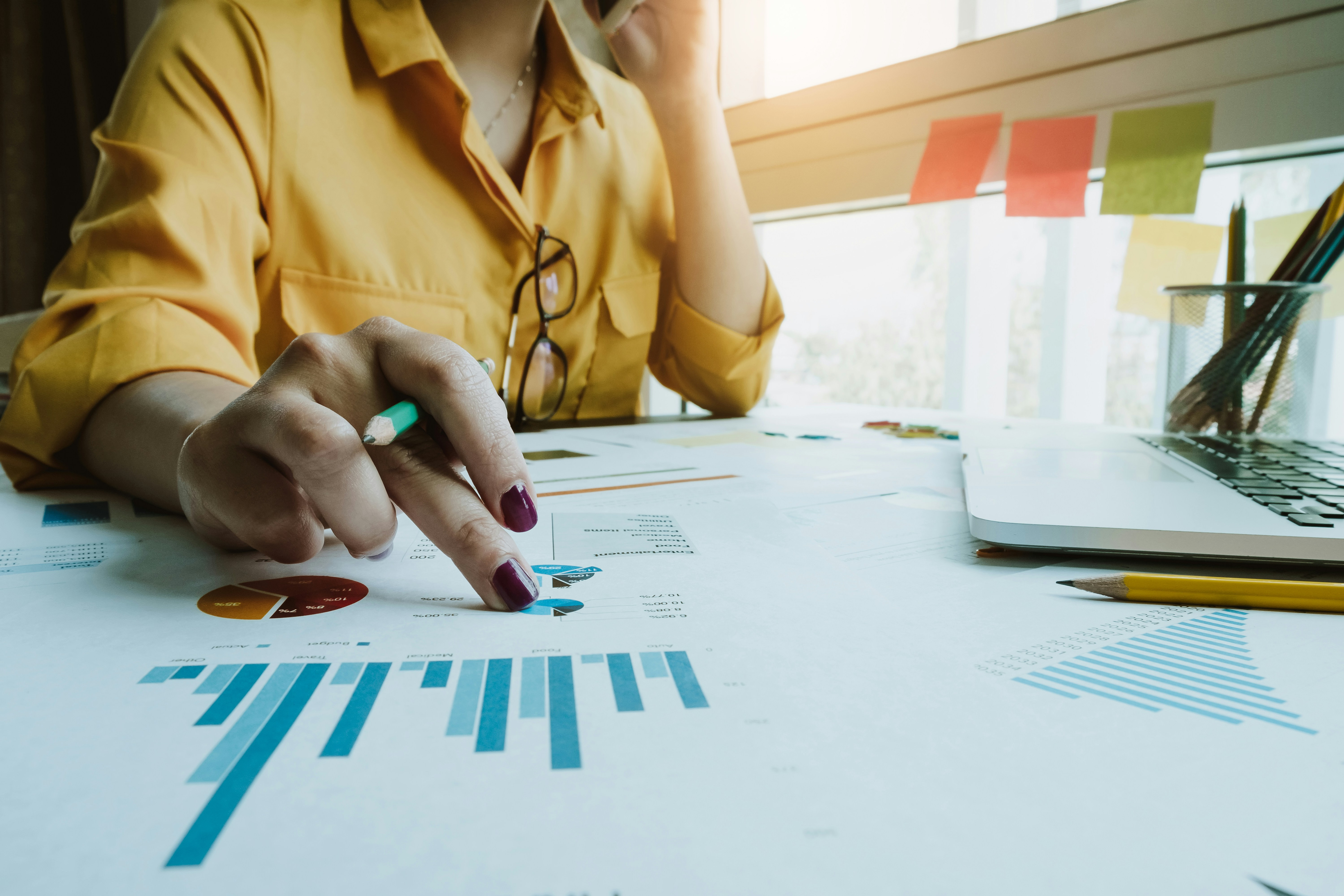 En kvinna sitter vid ett bord med en bärbar dator och en penna.