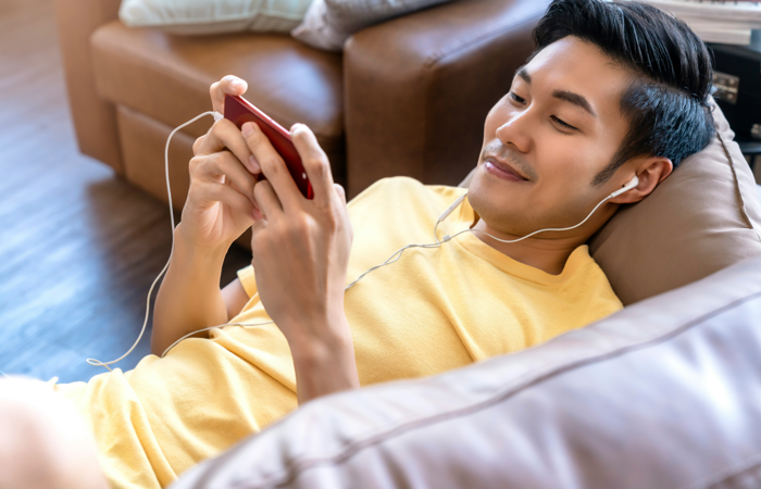 En man som ligger på en soffa och lyssnar på musik.