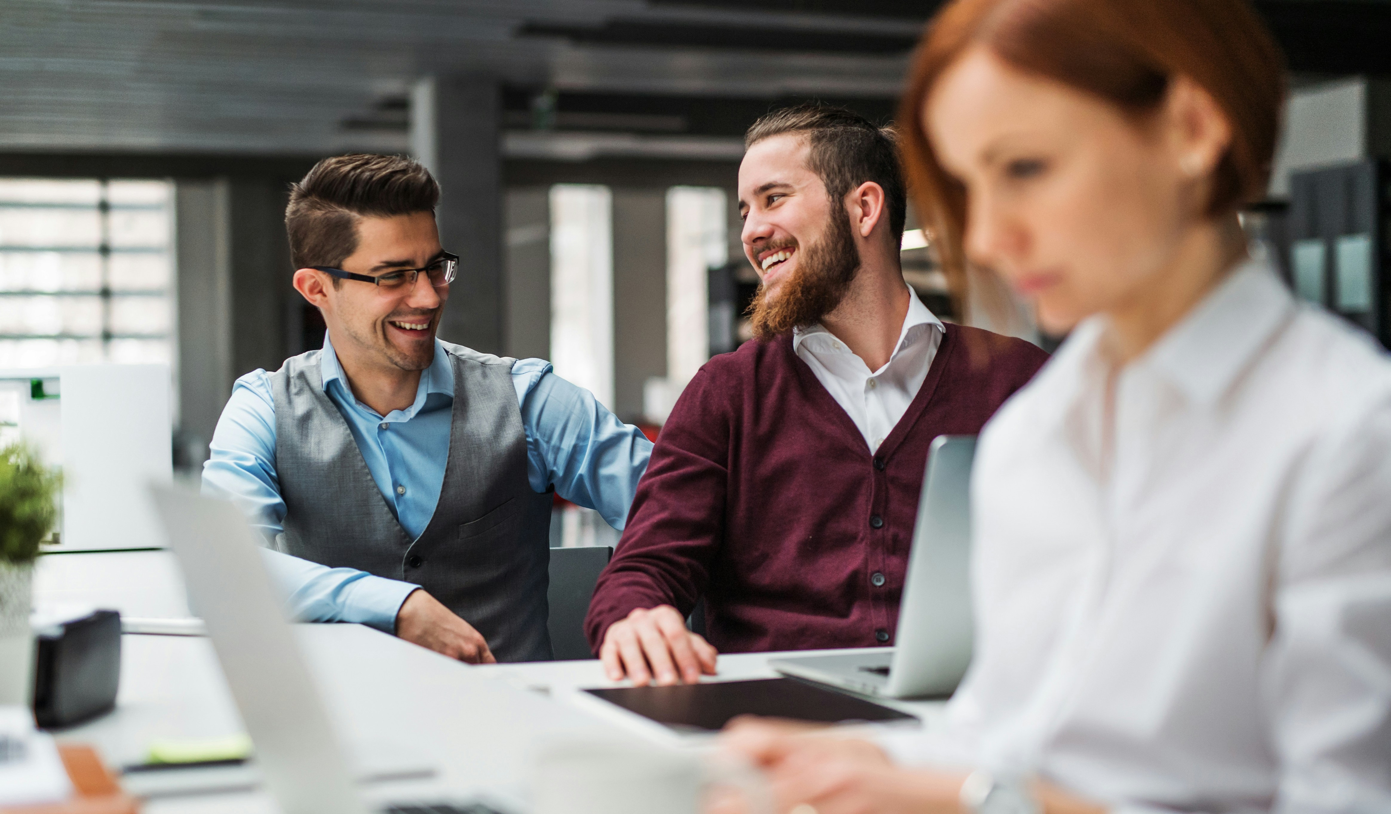 En grupp människor som sitter runt ett bord med bärbara datorer.