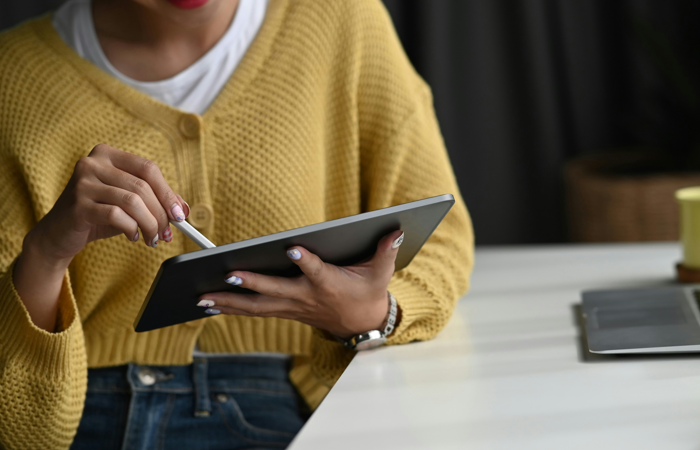 En kvinna sitter vid ett bord med en surfplatta.