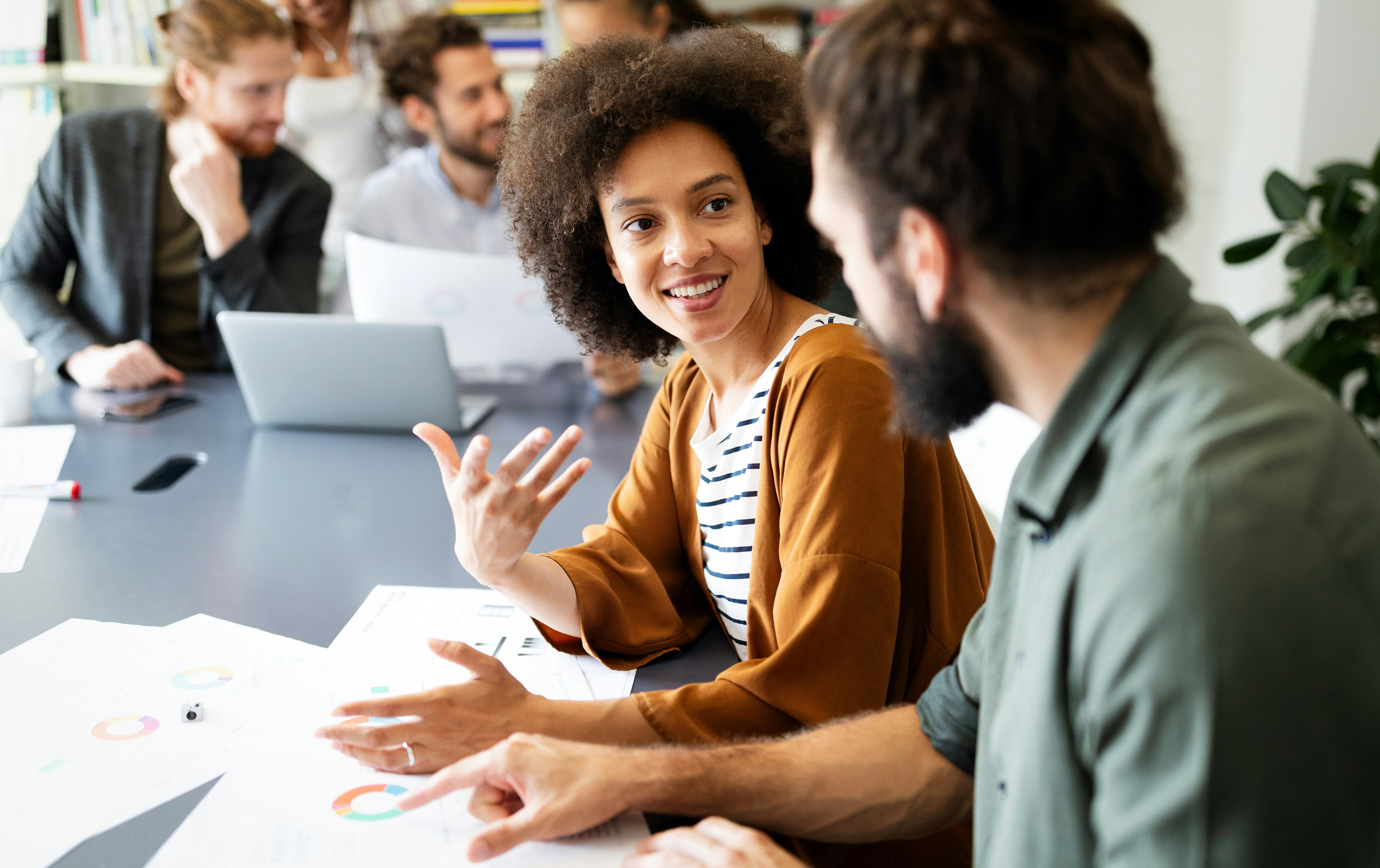 En grupp människor som sitter runt ett bord med bärbara datorer.