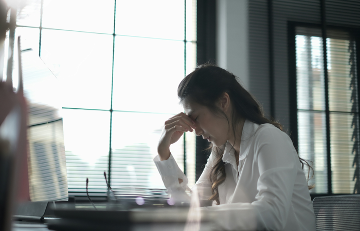 En kvinna sitter vid ett skrivbord framför en bärbar dator.