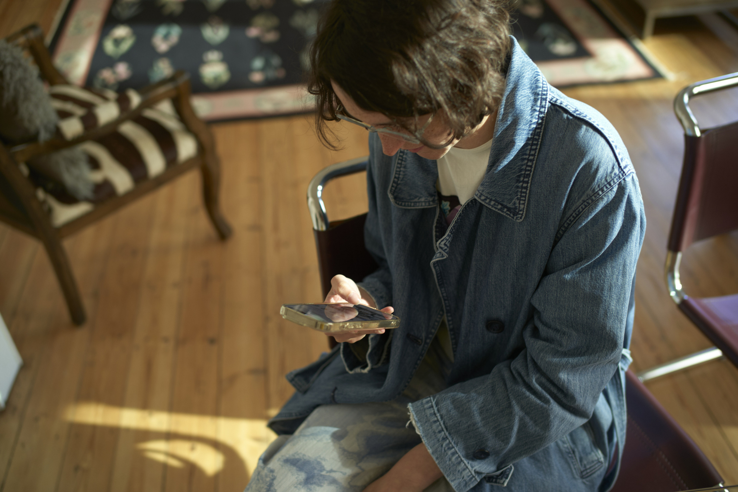 En person som sitter på en stol och tittar på en mobiltelefon.