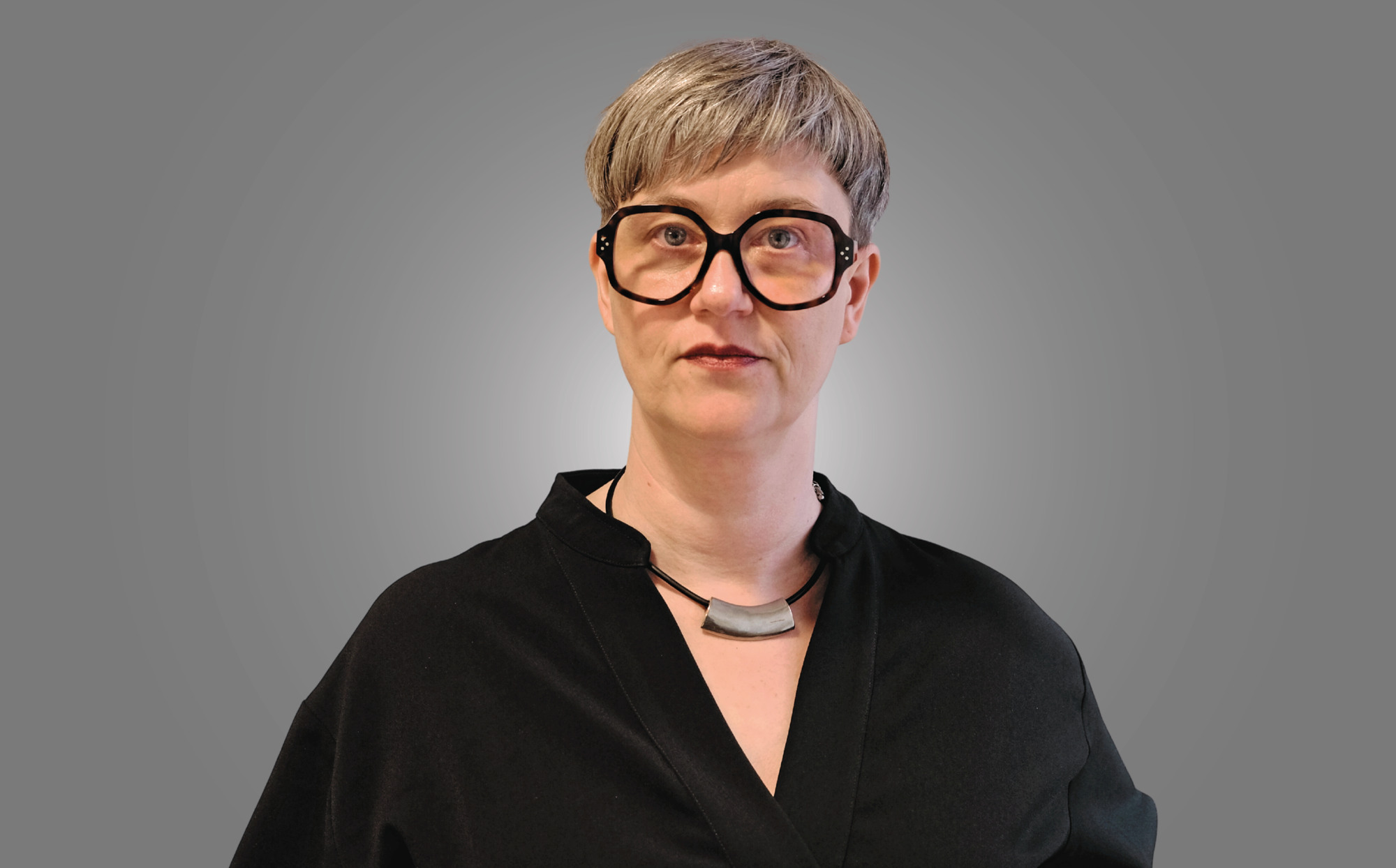 En kvinna med glasögon och svart skjorta.