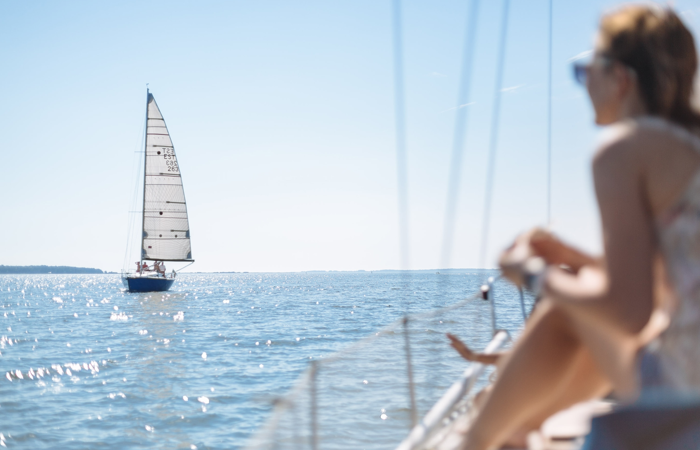 En kvinna sitter på en båt och tittar på en segelbåt