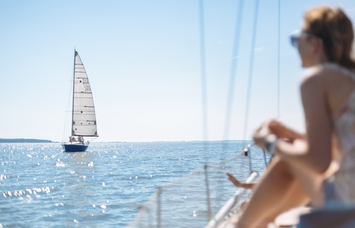 En kvinna sitter på en båt och tittar på en segelbåt