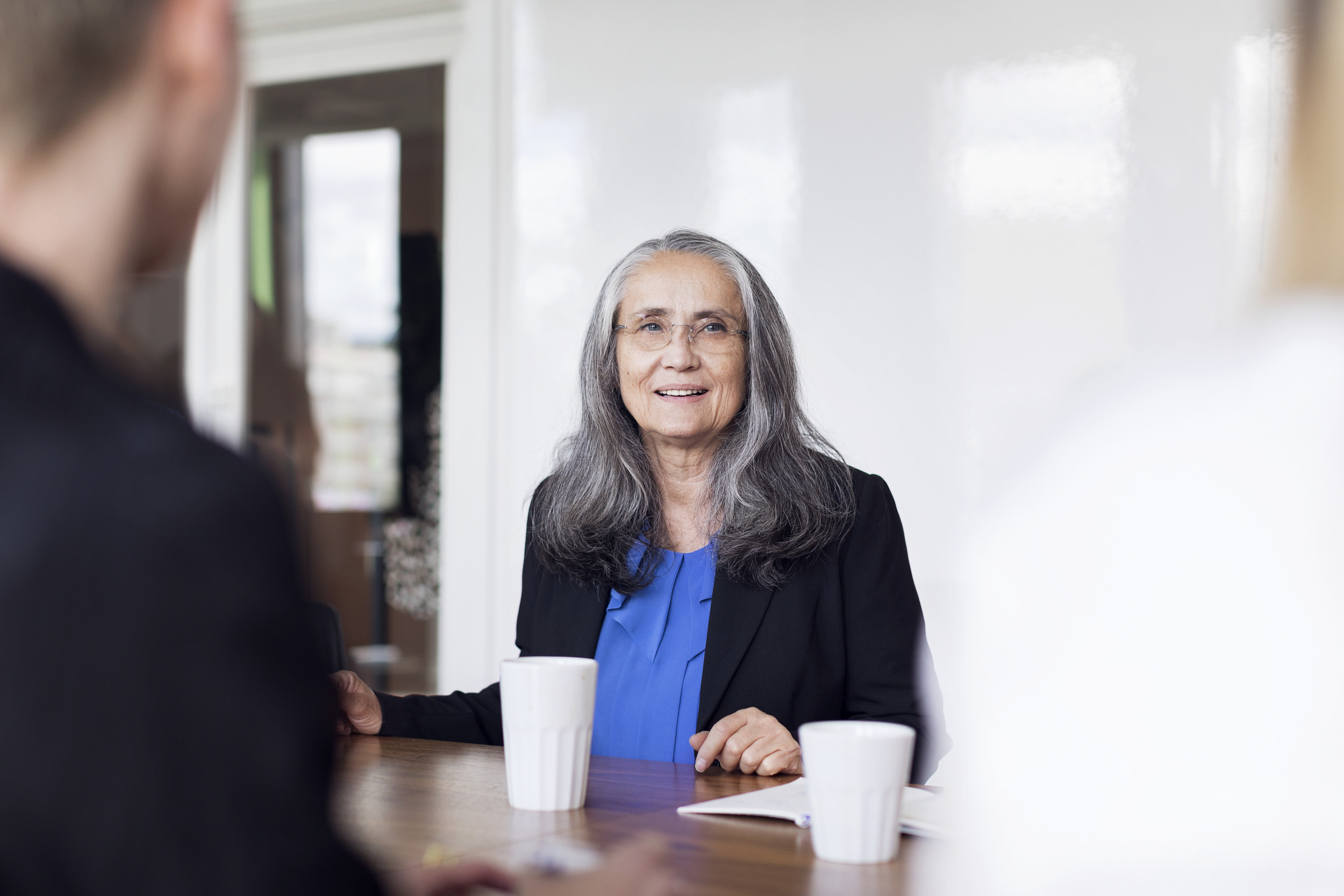 En kvinna sitter vid ett bord med en kopp kaffe.