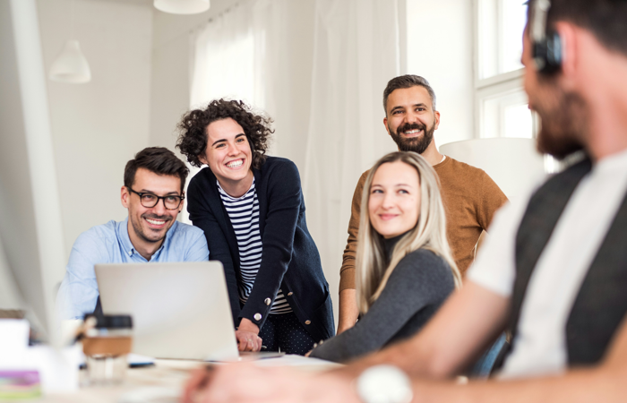 En grupp människor som sitter runt en bärbar dator