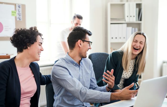 En grupp människor som sitter runt en bärbar dator