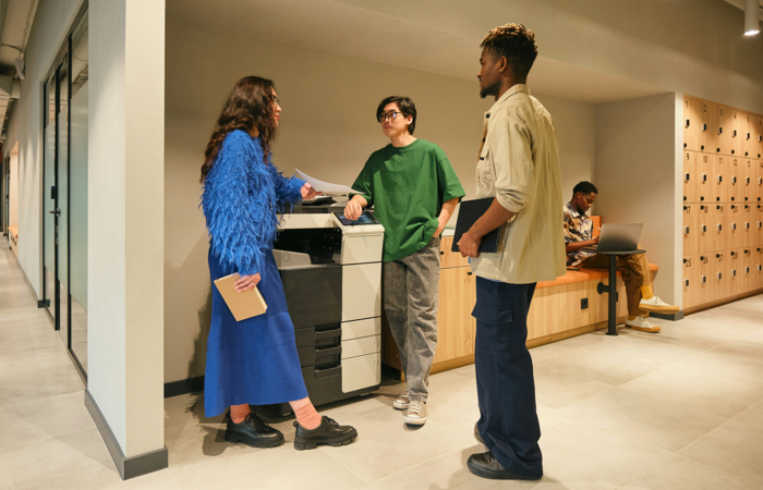 En grupp människor som står runt ett printer. 