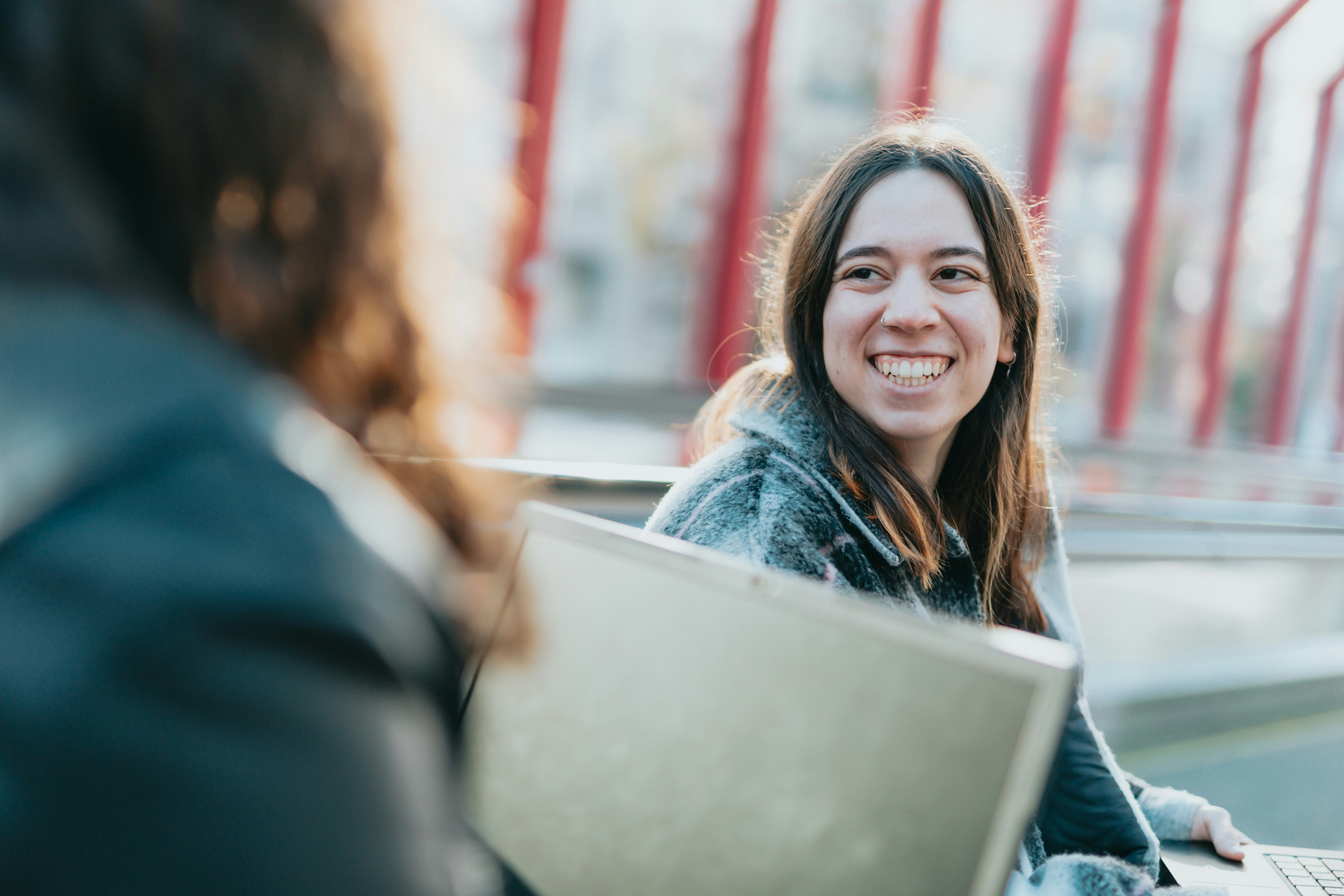 En kvinna som sitter framför sin kompis och ler. 