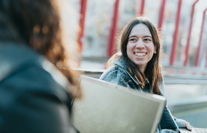 En kvinna som sitter framför sin kompis och ler. 
