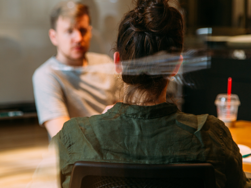 En man och en kvinna sitter vid ett bord framför en projektorskärm