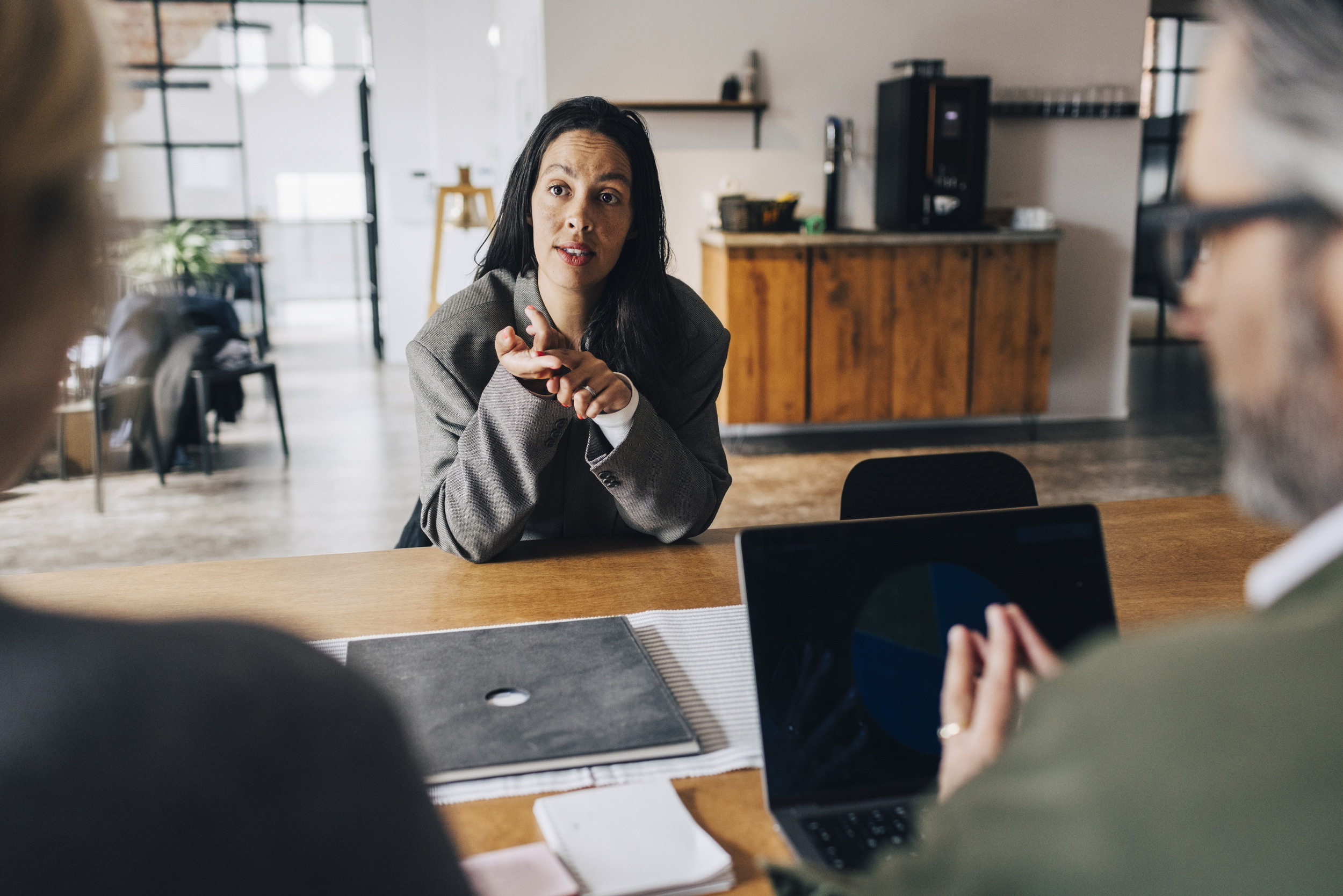En kvinna sitter vid ett bord framför en bärbar dator.